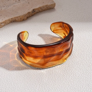 Macro view of vintage amber acrylic open bangle with irregular wave design and texture