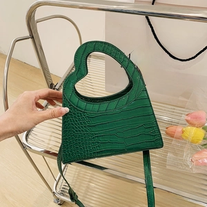 Detail of green crocodile texture handbag with unique heart-shaped cutout handle