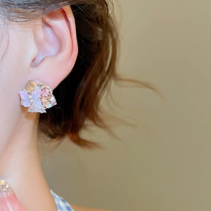 Detail of floral butterfly stud earrings with pink and purple crystals on the ear