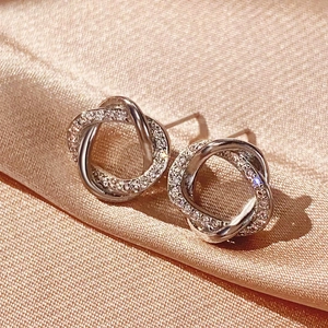 Detail of silver twisted knot earrings featuring polished and zircon-paved bands on silk