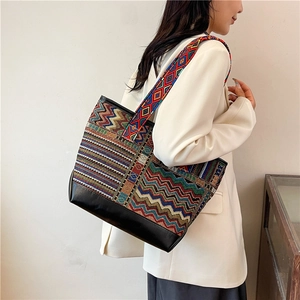 Ethnic bohemian canvas tote bag with black leather base and wide strap shown by a model