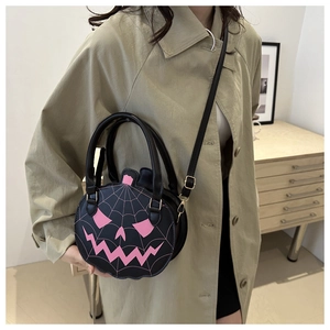Detail of black pumpkin handbag featuring pink Jack-o'-lantern face and spider web stitching