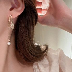 Elegant gold tulip earrings with long pearl tassels shown worn by a model