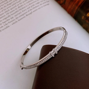 Detail view of silver H-logo bracelet with cubic zirconia on leather and book background