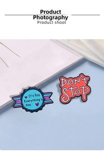 Close-up of enamel letter pins with positive text on blue and white fabric background