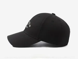 Detail of black cotton baseball cap showing white letter embroidery and side texture