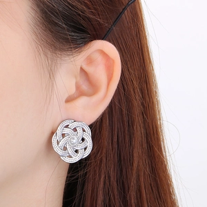 Gros plan de boucles d'oreilles fleur évidée en argent avec perle blanche sur modèle