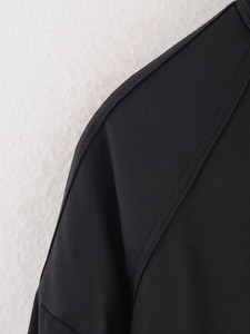 Dettaglio della spalla in tessuto twill nero con cuciture raffinate e alto contrasto