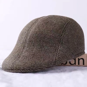 Detail of men's brown wool newsboy cap showing thick diagonal twill fabric texture