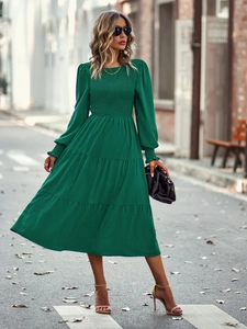 Détail d'une robe midi verte à manches longues avec buste froncé et ourlet à volants