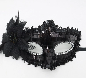 Macro view of black sequined masquerade mask with silk flower and feather details