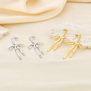 Detailed view of 18K gold and silver bow earrings with sparkling zircon accents
