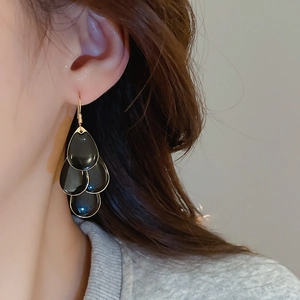 Detail of black tiered water-drop earrings with elegant gold-plated metal borders