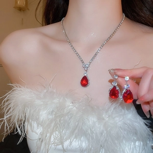 Detail of silver jewelry set with red waterdrop gems and diamonds on model