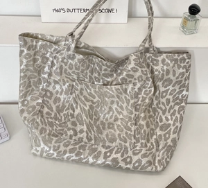 Macro shot of silver leopard print canvas tote bag showing metallic texture and front pocket