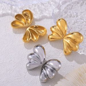 Minimalist wing-shaped titanium steel studs in gold and silver finishes on ice crystals