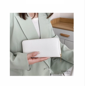 Macro detail of white lychee pattern PU leather long wallet with golden zipper held by model
