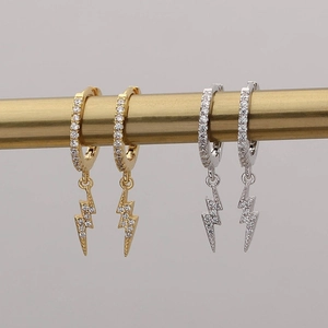 Detail of lightning bolt earrings with white zircons in gold and silver finishes