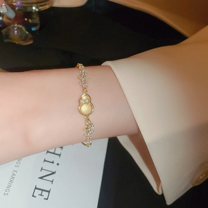 Detailed close-up of a golden gourd charm bracelet with zircon inlays worn on a wrist