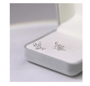 Macro shot of silver bow stud earrings on a grey velvet jewelry display box