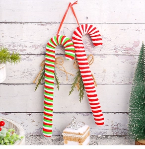 Macro detail of red and white striped plush candy cane ornaments with pine and twine bow
