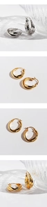 Makro-Detail von gedrehten Creolen in Gold und Silber auf einem Glasdekor