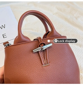 Detailed close-up of the silver toggle closure on a brown pebble leather bucket bag