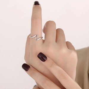 Close-up of minimalist silver wavy ring worn on index finger with glossy finish