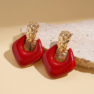 Detail of vintage geometric red resin earrings with hammered gold metal texture on a stone