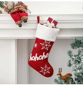 Macro detail of red knitted Christmas stocking with white plush cuff hanging on a fireplace