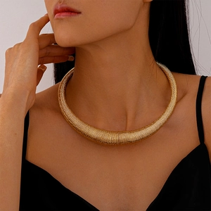 Detail of gold metal choker featuring a textured horizontal ribbed surface on neck
