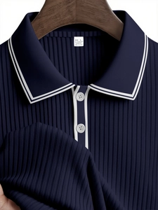 Close-up of navy blue striped polo shirt collar and ribbed texture on wooden hanger