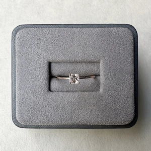 Close-up of square-cut moissanite ring in rose gold setting inside a grey jewelry box