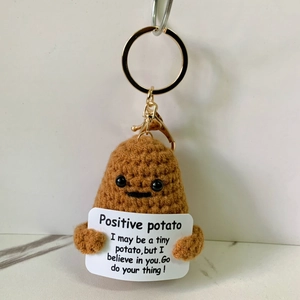 Detail of handmade crochet brown potato keychain with positive quote card and gold clasp