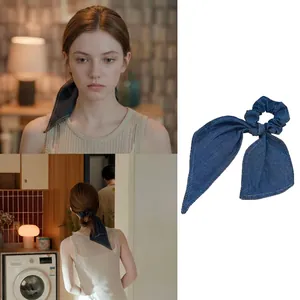 Close-up of blue denim bow hair tie with contrast stitching and streaming ribbons