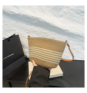 Detail of striped straw bucket bag with leather strap and silver metal buckle