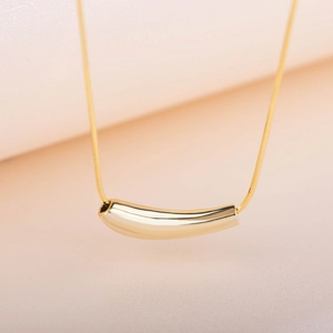 Detail of minimalist gold titanium necklace with a curved tube pendant on a snake chain