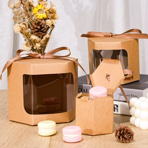 Macro detail of hexagonal kraft gift boxes with PVC window and brown ribbon on wooden desk