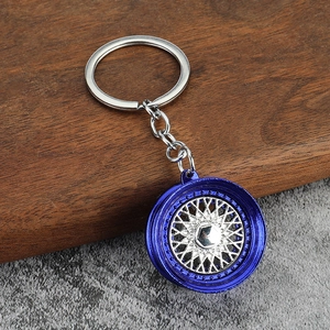 Detail of multi-spoke car wheel keychain with blue plating and silver spokes on wood