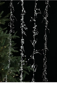 Detailed shot of Christmas bead chains with silver snowflakes and pearls on black background