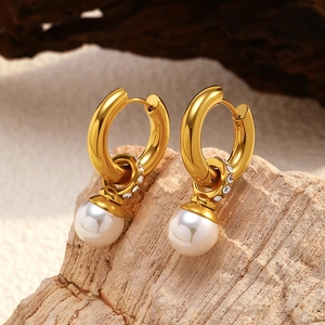 Detailed macro of gold plated hoop earring with hanging pearl and shimmering white zircon stones