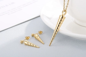 Macro shot of gold spiral cone necklace and earrings set on a textured grey background