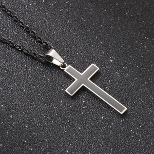 Close-up of hip hop silver and black cross pendant with textured twist chain on dark background