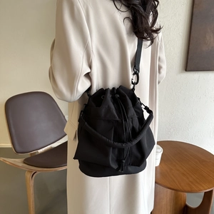 Détail d'un sac seau noir à cordon en nylon texturé avec bandoulière réglable pratique