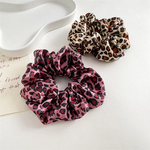 Detailed view of pink and beige leopard print satin scrunchies with smooth texture