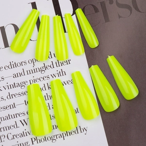 Close-up of gloss neon yellow coffin press-on nails arranged on a fashion magazine