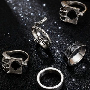 Macro shot of silver vintage punk rings set including snake and skull motifs on dark background