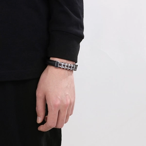 Dettaglio del bracciale da uomo intrecciato in pelle con chiusura in metallo argento al polso