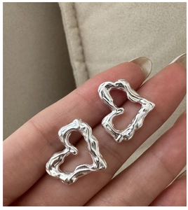 Dettaglio di orecchini a cuore in argento S925 con texture irregolare in metallo liquido