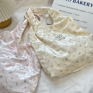 Detailed texture of pink and beige velvet tote bags with bear print in a warm lifestyle setting